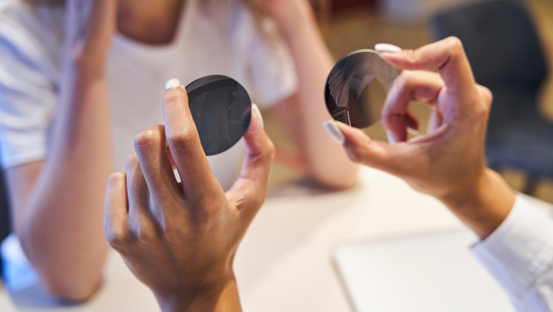 female optician hands holding round lenses comparison 