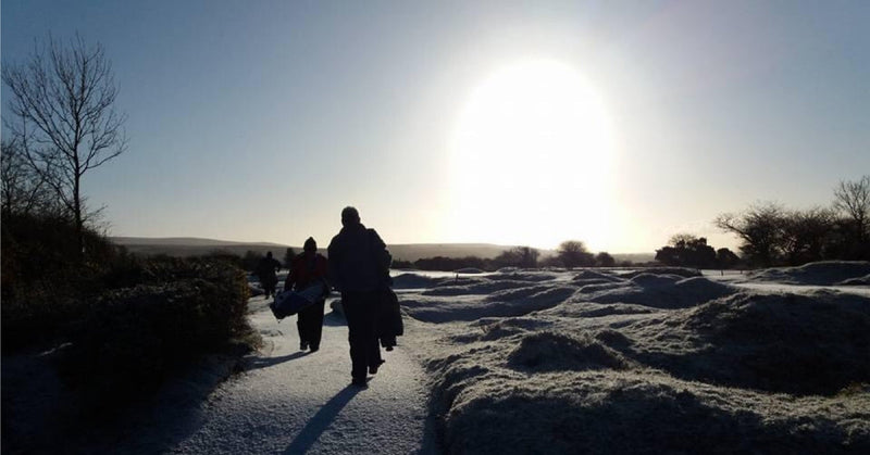 golfers walking through snow on sunny day