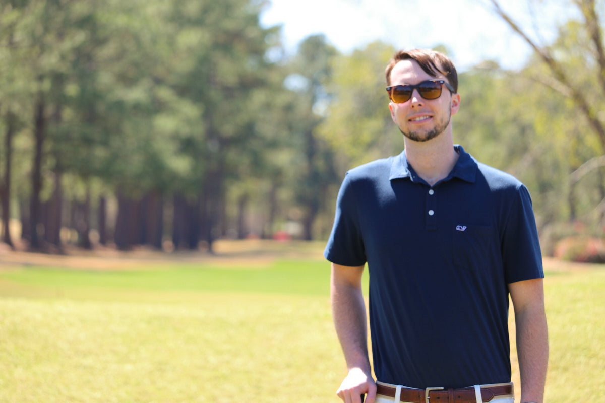 Person on golf course wearing a blue polo shirt and sunglasses.