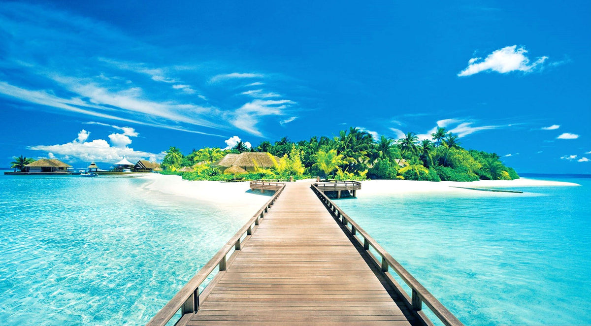 Bridge leading to a small sunny tropical island with vegetation.
